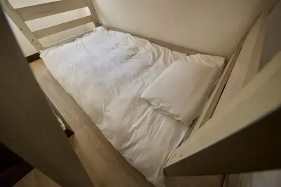 a small white bed in a small room at Hajime Stay in Tokyo