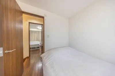 a bedroom with a white bed and a wooden door at 9-min walk to Ikebukuro Station, 1-min walk to Kanamecho Station Max 8 guests 70 sqm Free parking Direct access to Shinjuku, Shibuya, Ueno in Tokyo