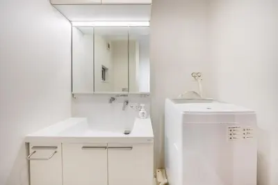 a white bathroom with a sink and a mirror at 9-min walk to Ikebukuro Station, 1-min walk to Kanamecho Station Max 8 guests 70 sqm Free parking Direct access to Shinjuku, Shibuya, Ueno in Tokyo