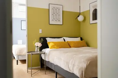 a bedroom with a bed with yellow pillows and a table at ARiA STAY SHINAGAWA in Tokyo