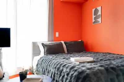 a bedroom with a bed with an orange wall at ARiA STAY SHINAGAWA in Tokyo