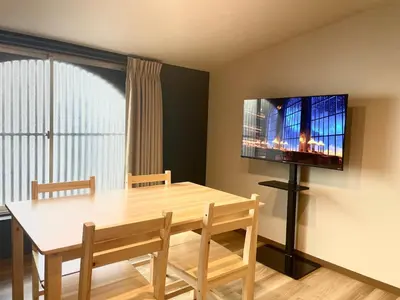 a dining room with a table and a flat screen tv at Hotel Kototoi Juku HAKU in Tokyo