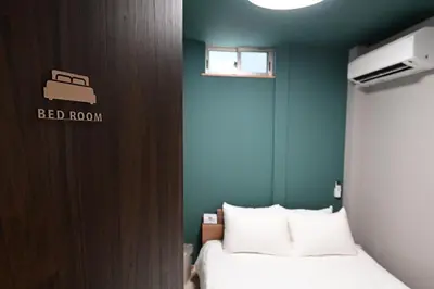 a bedroom with a bed and a green wall at Rakuna Inn Nizi - Oshiage 2 - Vacation STAY 46832v in Tokyo