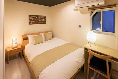 a bedroom with a bed and a desk and a window at Cityzen Tokyo in Tokyo