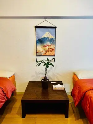 a room with two beds and a table with a potted plant at Tokyo Ami House in Tokyo