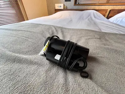 a black flashlight sitting on top of a bed at \u6771\u5dba\u753a47 in Tokyo