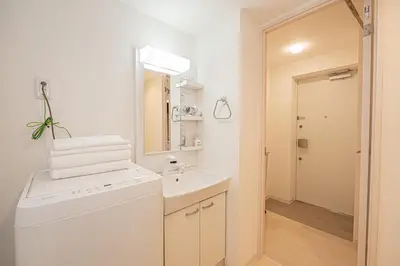 a white bathroom with a sink and a washing machine at Japan House Komagome Apartment\u65b0\u7bc9\u99d2\u8fbc\u99c5\u5f92\u6b695\u5206 in Tokyo