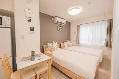 a small room with two beds and a table and a desk at Japan House Komagome Apartment\u65b0\u7bc9\u99d2\u8fbc\u99c5\u5f92\u6b695\u5206 in Tokyo
