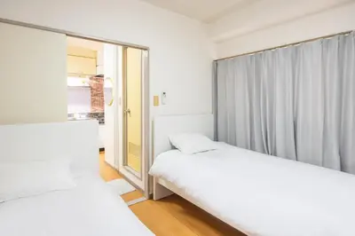 two beds in a room with a window at Ikebukuro 8 min walk, Kanamecho 6 min walk, 25sqm room, 2 guests, Direct access to Shinjuku, Shibuya, Tokyo, Ueno, 2 single beds in Tokyo