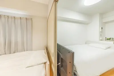 a bedroom with two beds and a mirror at Ikebukuro 8 min walk, Kanamecho 6 min walk, 25sqm room, 2 guests, Direct access to Shinjuku, Shibuya, Tokyo, Ueno, 3 single beds in Tokyo