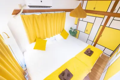 a bedroom with two beds and yellow curtains at Max 9 people 3 min taxi Ikebukuro Station Tiffany Blue yellow Room \u6700\u59279\u540d \u6c60\u888b in Tokyo