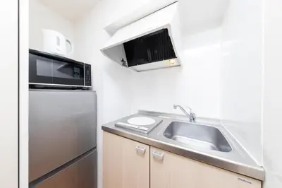 a kitchen with a sink and a microwave and a refrigerator at Shinjuku Homely Stay in Tokyo
