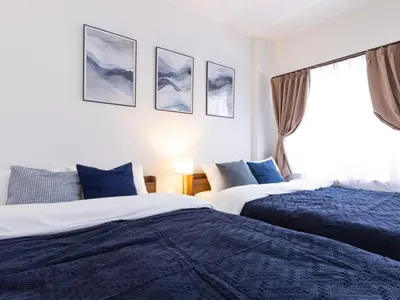 two beds in a bedroom with blue and white at Tokyo Stay Aoto in Tokyo