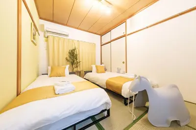 a room with two beds and a chair in it at TDR\u8eca9\u5206 3BR 5Bed \u5922\u306e\u7d9a\u304d\u3092\u697d\u3057\u3081\u308b\u5bbf -TAMU-LAND Kasai- in Tokyo