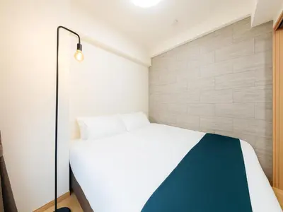 a bedroom with a white bed and a wall at Shinjuku,5min Walk to Higashi-Shinjuku sta & Shinjuku Sta,King Bed,ree Wi-Fi in Tokyo