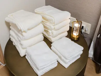 a pile of towels on a table with a candle at Shinjuku,5min Walk to Higashi-Shinjuku sta & Shinjuku Sta,King Bed,ree Wi-Fi in Tokyo