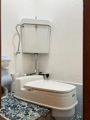 a white toilet in a bathroom with a tile floor at nestay suite tokyo Takadanobaba in Tokyo