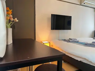 a room with a table and a tv on the wall at nestay suite tokyo Takadanobaba in Tokyo
