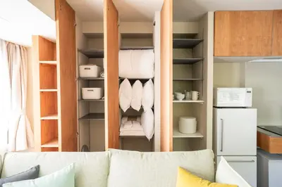 a living room with a couch and a open closet at NEIJU Apartment Hotel - Live Like a Local in Nakano - Direct Shinjuku Access in Tokyo