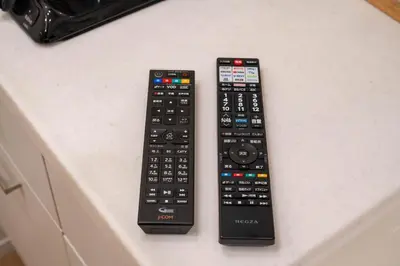 two remote controls sitting on top of a counter at \u5c0f\u718a\u306e\u5bb6 129Ta in Tokyo