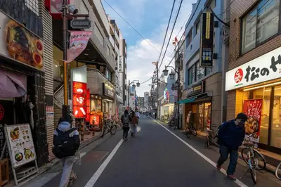 a group of people walking down a street with buildings at \u5c0f\u718a\u306e\u5bb6 129Ta in Tokyo