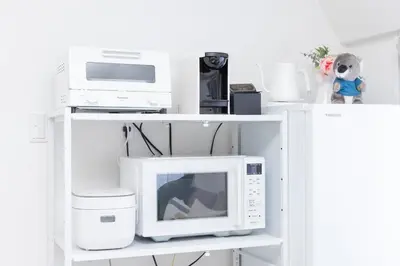 a white shelf with a microwave and other appliances at \u5c0f\u718aAnnex 129Tb in Tokyo