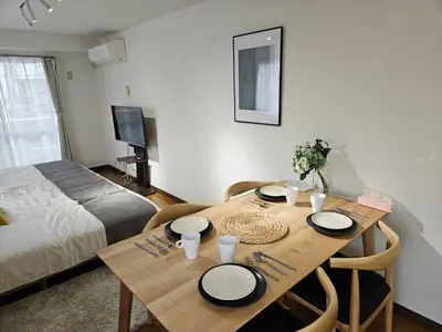 a room with a wooden table with chairs and a bed at \u30db\u30c6\u30eb\u30ec\u30b9\u30dd\u30ef\u30fc\u30eb303 in Tokyo