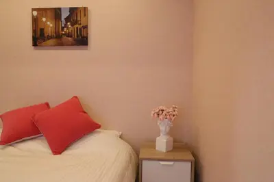 a bedroom with a bed with two red pillows and a vase with flowers at Maple Ginkgo Views Autumn Stay Up To 8 in Tokyo