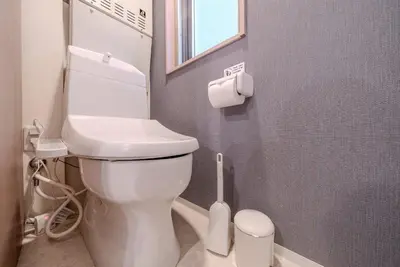 a bathroom with a toilet with a toilet brush at \u30d1\u30fc\u30af\u30b7\u30fc\u30c9\u65b9\u5357\u753a in Tokyo
