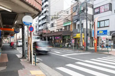 a busy city street with a car driving down the street at \u30d1\u30fc\u30af\u30b7\u30fc\u30c9\u65b9\u5357\u753a in Tokyo
