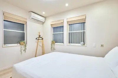 a bedroom with a white bed and windows at STAY ARI Higashishinjuku in Tokyo