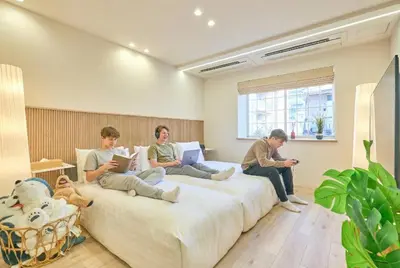 three people sitting on a large bed in a room at STAY ARI Higashishinjuku in Tokyo