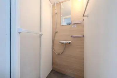 a shower in a bathroom with a wooden wall at T-Flat SASAZUKA in Tokyo