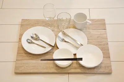 a table with white plates and silverware on a cutting board at Kokoon Hotel Ebisu in Tokyo