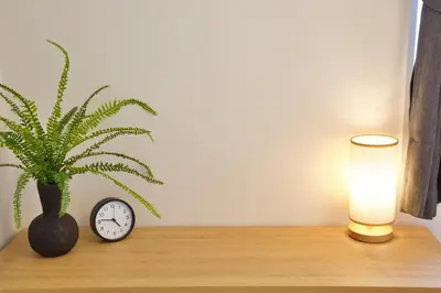 a table with a plant and a clock and a lamp at Kokoon Hotel Ebisu in Tokyo