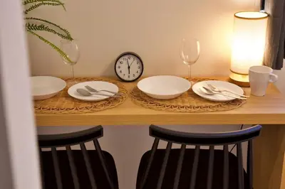 a table with plates and wine glasses and a clock at Kokoon Hotel Ebisu in Tokyo
