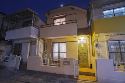 a yellow house with a white fence in front of it at \u5800\u52074\u4e01\u76ee\u6238\u5efa in Tokyo