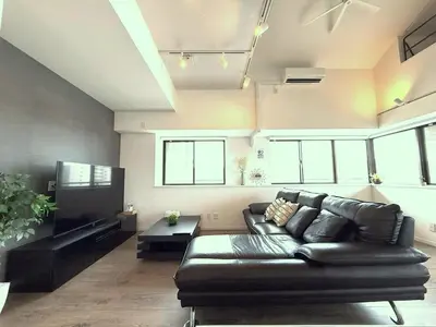 a living room with a black leather couch and a tv at 東京最上階の豪邸ステイ 最上階270度ビュー&スカイツリーを望む 最大8名貸切 上野浅草秋葉原近く 無料WiFi アルカディア北千住 in Tokyo