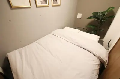 a bed with white sheets and a plant in a room at Heureux\u690e\u540d\u753a202 in Tokyo