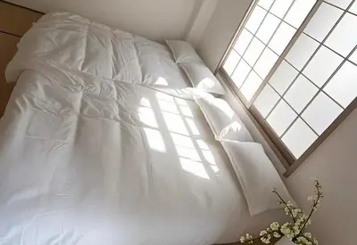 a bed with white sheets and pillows and a window at \u6c5f\u5143Skytree in Tokyo