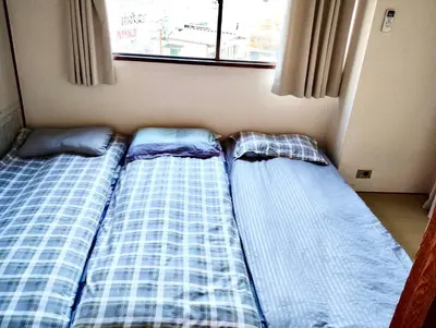 two beds sitting next to each other in a room at Shinjuku Okubo Henna House in Tokyo