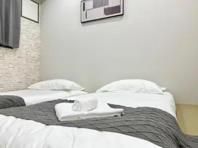 two beds with white towels and a microwave on the wall at \u30af\u30ea\u30b9\u30bf\u30eb\u9ad8\u7530\u99ac\u5834101 in Tokyo