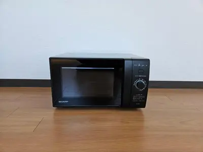 a black microwave oven sitting on a wooden floor at \u30db\u30c6\u30eb\u30ec\u30b9\u30dd\u30ef\u30fc\u30eb301 in Tokyo