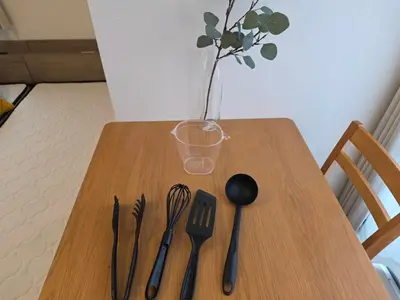 a wooden table with utensils and a vase with a plant at \u30db\u30c6\u30eb\u30ec\u30b9\u30dd\u30ef\u30fc\u30eb301 in Tokyo