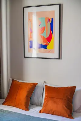 a bed with two orange pillows and a picture on the wall at 2 min by train to Shibuya New 3rd floor 19 square meters in Tokyo
