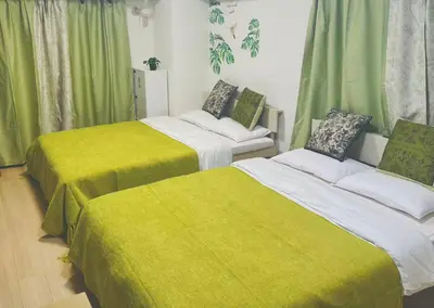 two beds in a room with green curtains at Shinjuku\u65b0\u5bbf\u516c\u5712 in Tokyo
