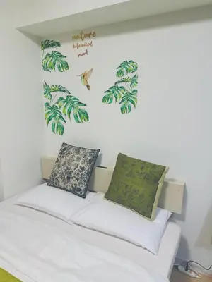 a bedroom with a bed with green leaves on the wall at Shinjuku\u65b0\u5bbf\u516c\u5712 in Tokyo