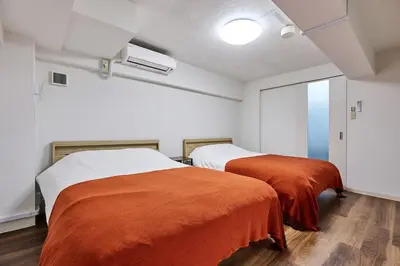 two beds with orange sheets in a room at G&R House Premium in Tokyo