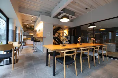 a dining room with a large wooden table and chairs at E10 Hostel in Tokyo