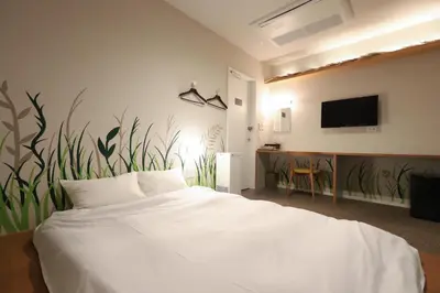 a bedroom with a white bed and a wall with plants at E10 Hostel in Tokyo